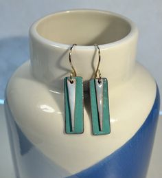 a pair of earrings sitting on top of a white vase