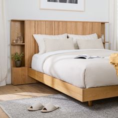 a bed with white linens and wooden headboard next to a pair of slippers