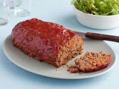 meatloaf with ketchup on a plate next to a salad