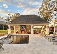 an outdoor pool with lounge chairs and tables around it