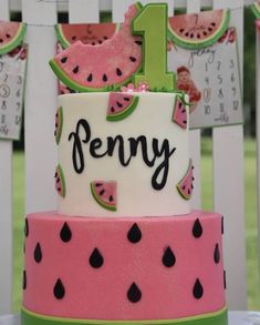 a pink and green cake with watermelon slices on it's sides, the number one is for penny