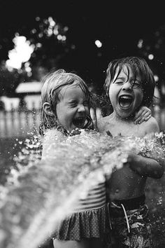 two young children playing in the water with their mouths open and one child holding his head