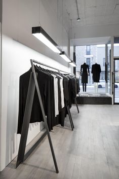 clothes are hanging on racks in a clothing store, with one light above the rack