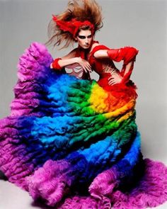 a woman in a colorful dress with her hair flying through the air, posing for a photo