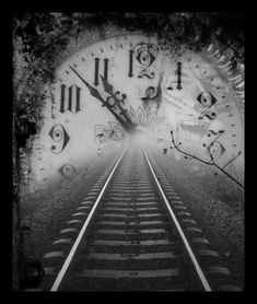 a black and white photo of a train track with a clock on the wall behind it