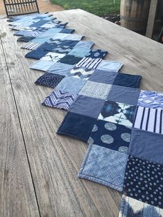 several pieces of blue quilt laid out on a picnic table with chairs in the background