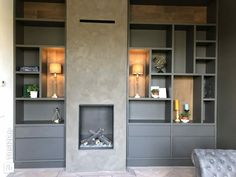 a living room filled with furniture and a fire place next to a wall mounted bookcase