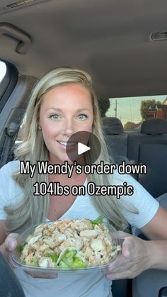 a woman sitting in the back seat of a car holding a plate of food