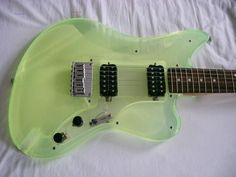 a green electric guitar sitting on top of a white sheet