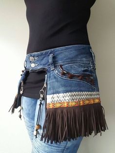 a woman is wearing a jean skirt with fringes on the bottom and an embellished belt around her waist