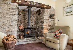 a living room with stone walls and a wood burning stove in the corner next to a chair