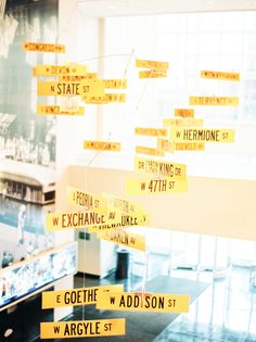 yellow street signs hanging from the ceiling in an office building with large windows behind them