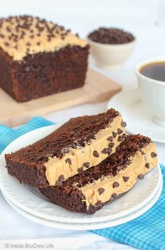 two slices of chocolate cake with peanut butter frosting on a plate next to a cup of coffee