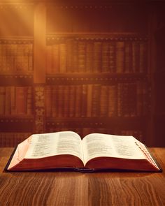 an open book sitting on top of a wooden table in front of a bookshelf