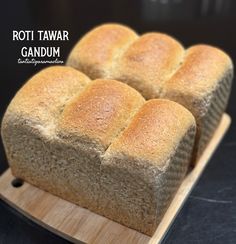 four loaves of bread sitting on top of a cutting board with the words roti tawar gandum