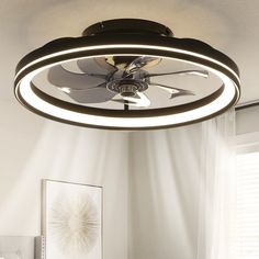 a ceiling fan is hanging from the ceiling in a room with white walls and windows