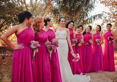 a group of women standing next to each other wearing pink dresses and holding bouquets