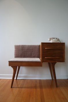 a chair sitting on top of a wooden table next to a wall with a phone on it