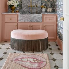 a bathroom with pink walls and marble counter tops, gold faucet, white rugs and floral wallpaper