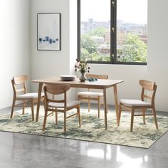 a dining room table with four chairs and a rug on the floor in front of it