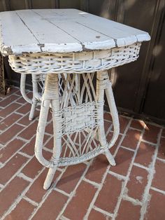 a white wicker table sitting on top of a brick floor