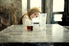 a woman sitting at a table with a glass in front of her and an empty cup next to her