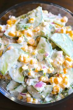 a glass bowl filled with corn and cucumber salad