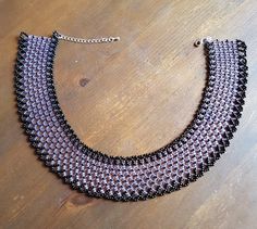 a black and silver necklace sitting on top of a wooden table