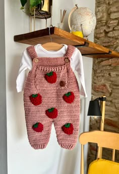 a baby's strawberry crochet outfit hanging on a clothesline