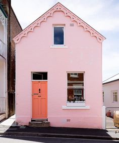 an instagram photo of a pink house with orange door and window in the front