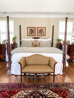 a large bed sitting in the middle of a living room next to a rug on top of a hard wood floor