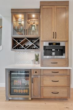 a kitchen with wooden cabinets and white counter tops, an open wine cooler in the center