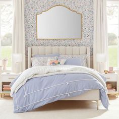 a bedroom with floral wallpaper and blue bedding in front of a large mirror