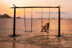 a woman sitting on a swing in the water