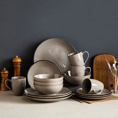 a stack of white dishes and cups sitting on top of a table