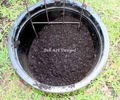 a metal bucket filled with dirt on top of grass