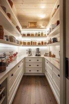 a kitchen with white cabinets and shelves filled with food on top of wooden flooring