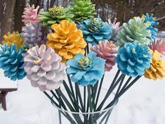 a vase filled with colorful flowers sitting on top of snow covered ground