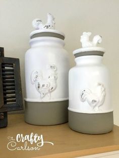 two white and gray vases sitting on top of a shelf