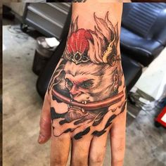 a person's hand with a tattoo on it and a cat wearing a crown