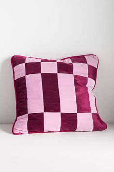 a pink and purple checkered pillow on a white surface