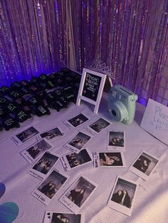 a table topped with pictures and a camera next to a purple wall covered in sequins