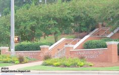 the entrance to columbia state university with trees and bushes on either side, in front of a red brick building