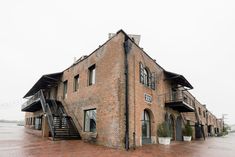 an old brick building with stairs leading up to the top floor and second story windows