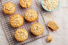 oatmeal muffins cooling on a wire rack next to a bowl of oats