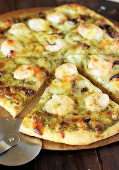 a pizza sitting on top of a wooden cutting board next to a knife and spatula