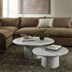 a living room with a couch, coffee table and books on the floor in front of it