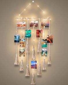 a group of pictures hanging on a wall with string lights and tassels attached to it