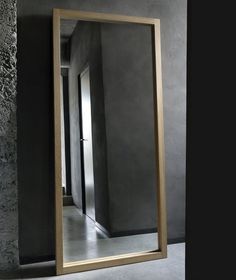 a large mirror sitting on top of a floor next to a stone wall in front of a doorway