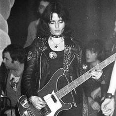 a woman holding a guitar in her hand while standing next to other people at a party